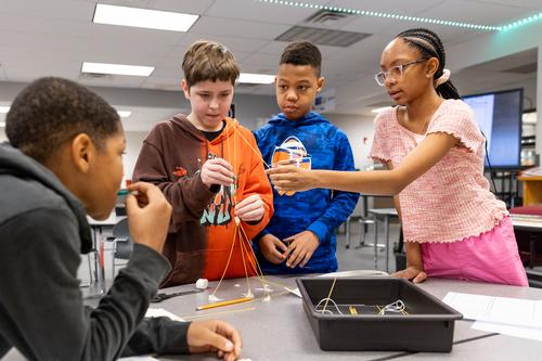 Students build a tower using dry spaghetti and marshmallows